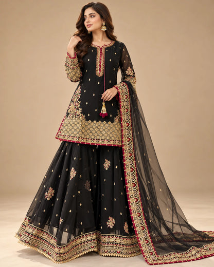 Model wearing black Pakistani festive sharara suit with intricate gold embroidery and matching dupatta