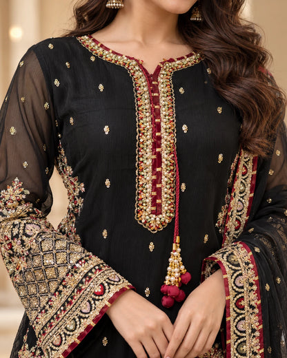 Close-up of black kameez neckline featuring gold beadwork, maroon piping and pearl tassels