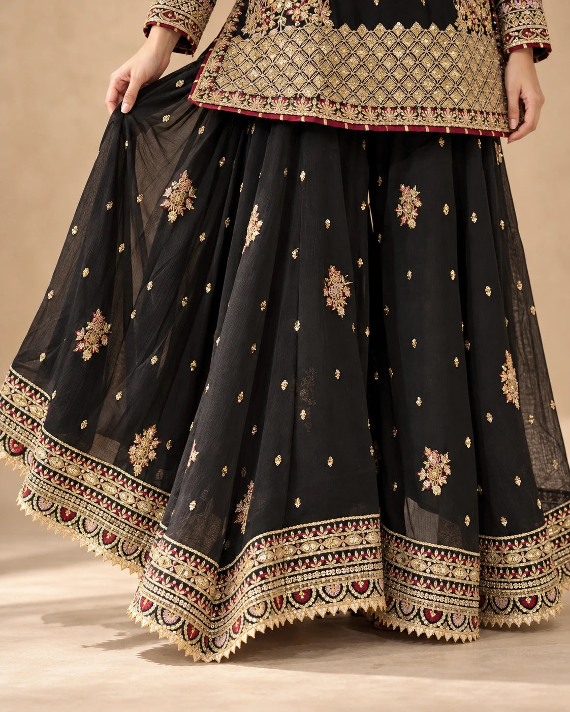 Flared black sharara trousers featuring scattered gold motifs and heavily embroidered borders