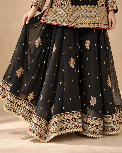 Flared black sharara trousers featuring scattered gold motifs and heavily embroidered borders