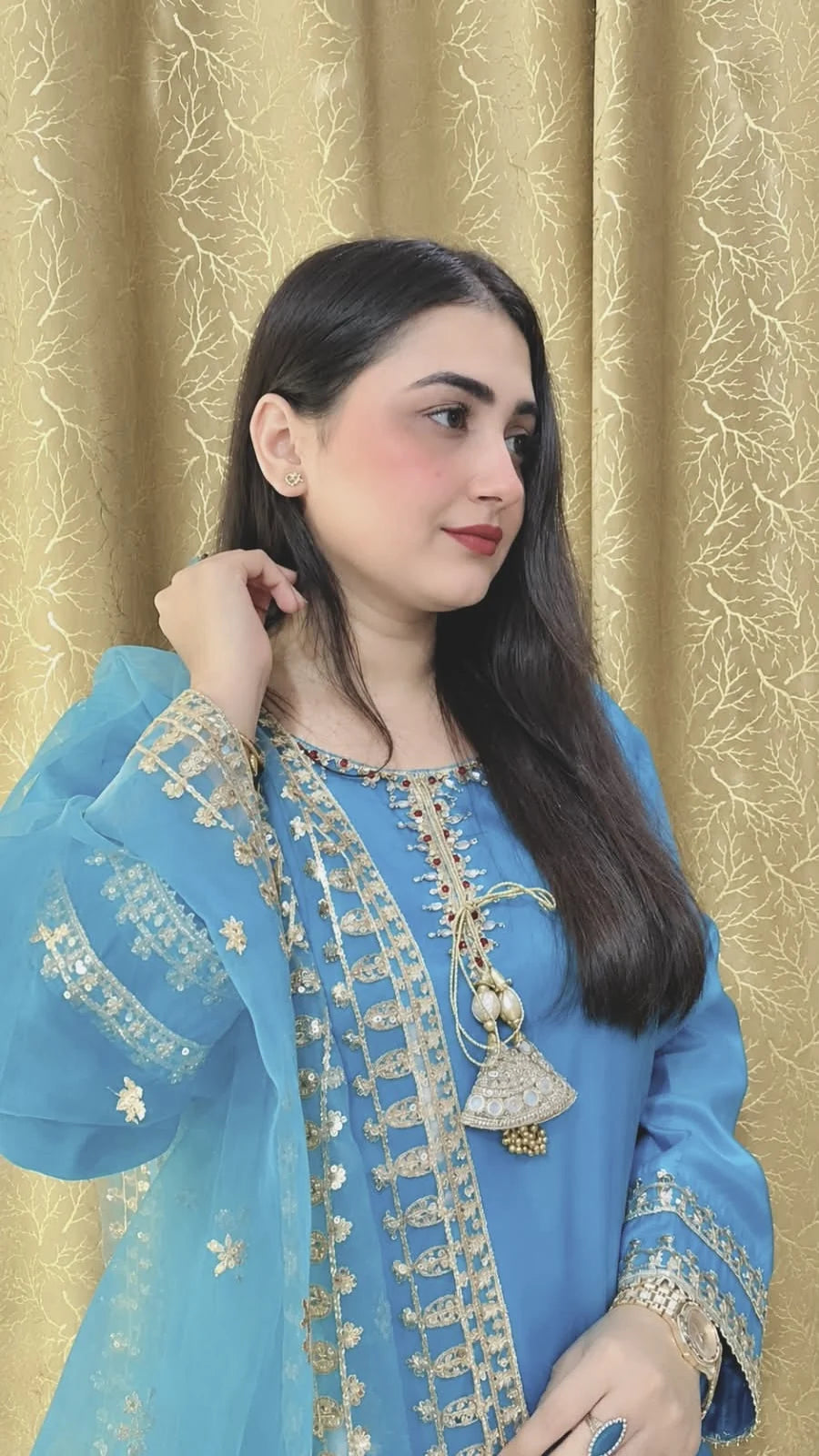 Side view of a sky blue embroidered China silk suit showing its decorated neckline and sleeve details.