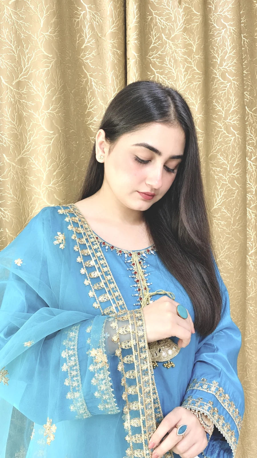Close-up of the sky blue China silk shirt featuring golden neckline embroidery, sequins and decorative tassels.